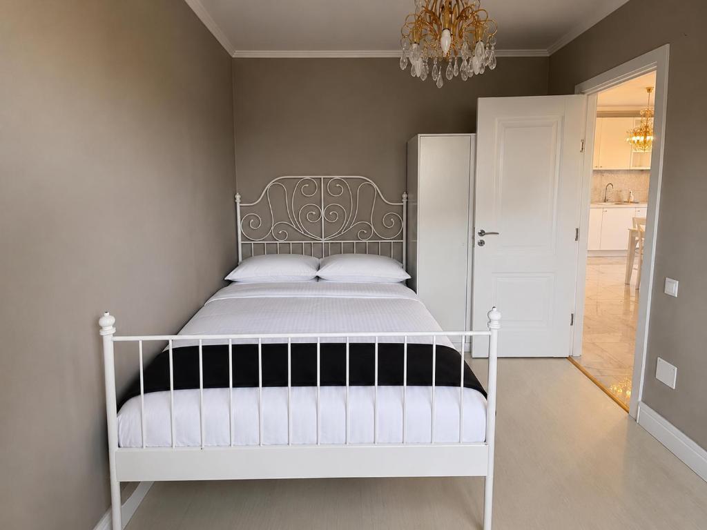 a bedroom with a white bed and a chandelier at YDA Apartament's in Baciu