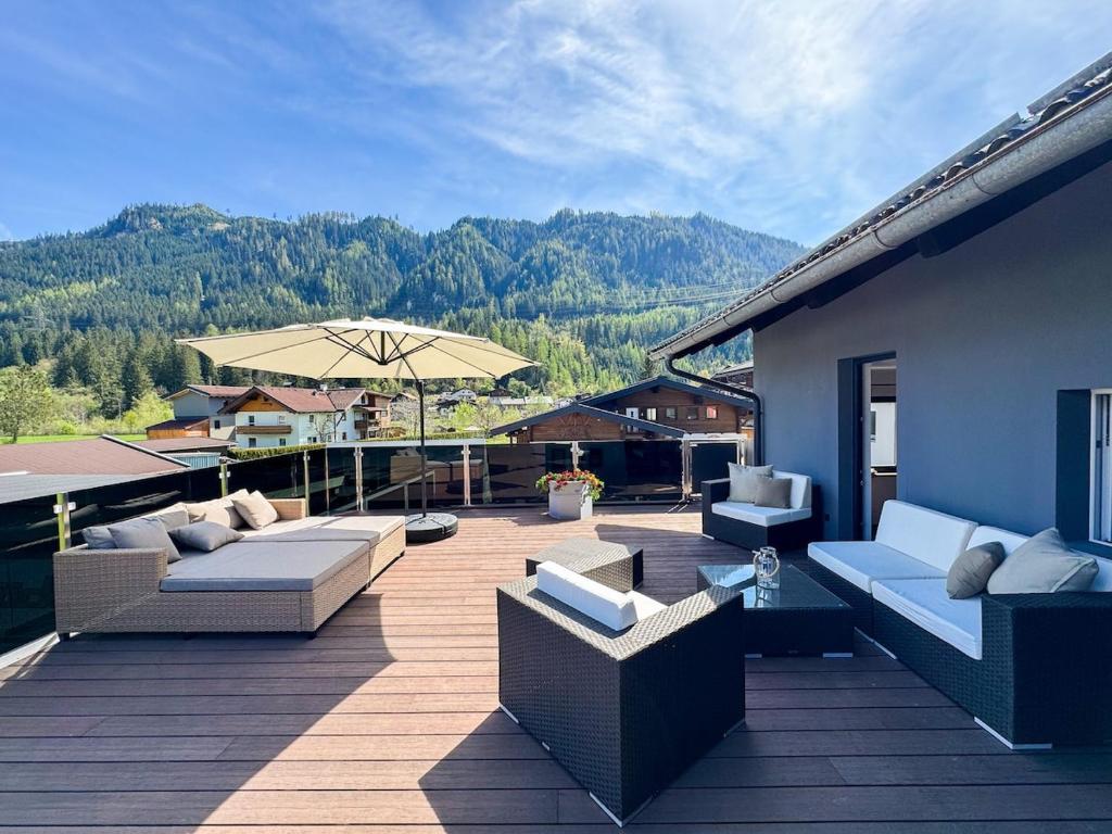 a patio with couches and an umbrella on a deck at Bramberg Hideaway mit großer Terrasse in Größing