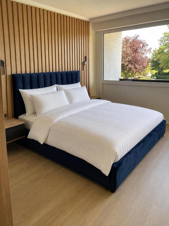 a large bed in a bedroom with a large window at Nordsee-Hotel in Butjadingen