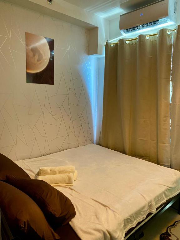 a room with a bed with a curtain and a picture of a moon at Casa Hiraya - Shore 2 Tower 2 in Manila