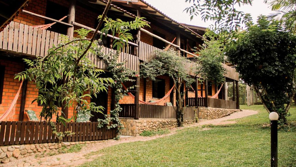 a building with a fence and trees in front of it at Pousada Aconchego do Rosa - Centrinho do Rosa in Praia do Rosa