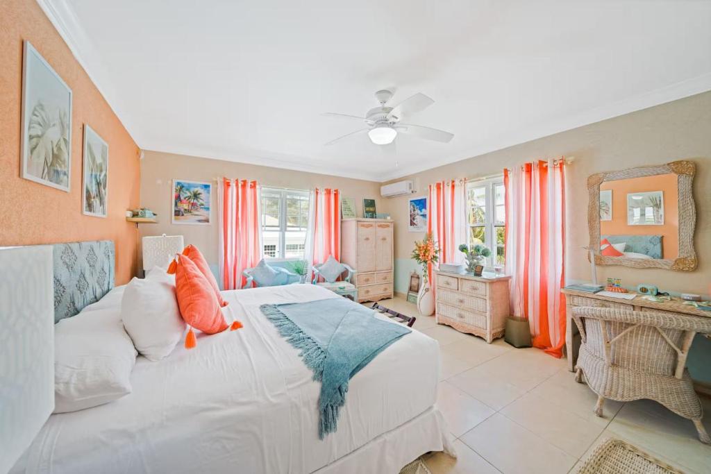 a bedroom with a white bed and orange curtains at Hidden Gem The Tropical - by ZenBreak in Christ Church