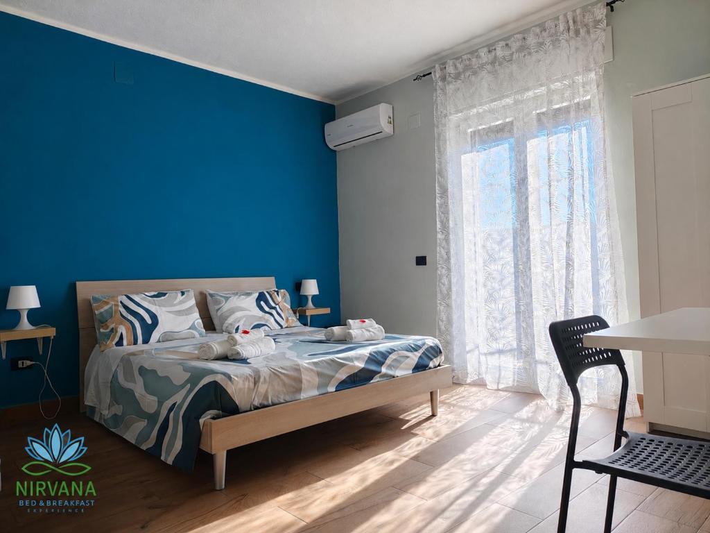 a bedroom with a bed with blue walls and a window at Nirvana Bed and Breakfast Experience in Noepoli