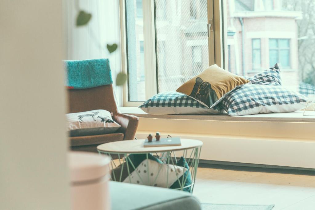 a living room with a window with pillows and a table at AP8 city & park apartement in Aalst