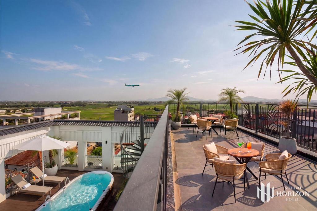 a balcony with tables and chairs and an airplane in the sky at Noi Bai Horizon Hotel & Spa in Noi Bai