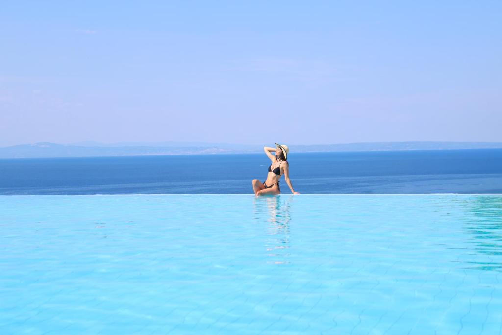 a woman in a bikini sitting in a pool of water at Alia Palace Hotel - Adults Only 16+ in Pefkochori