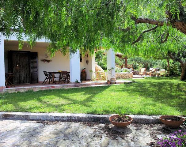 un cortile con una casa con un tavolo e un albero di Dolce Dormire Home Holiday a Castellammare del Golfo
