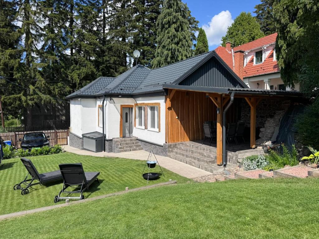 a house with a yard with a chair in front of it at Altum Mátra Vendégház in Mátraszentimre