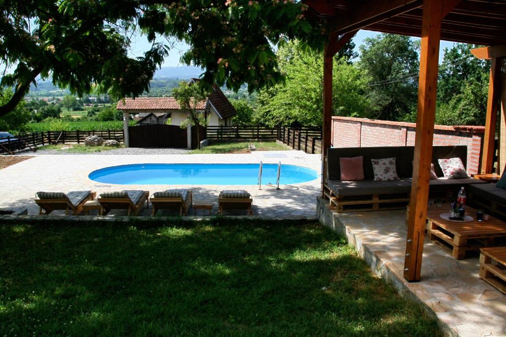 a backyard with a pool with chairs and a gazebo at Vila Daško in Lukavac