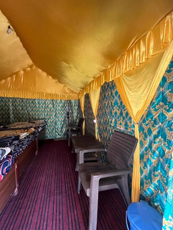 a room with two chairs and a bed in a tent at Chaukhamba Camp Stay in Chopta