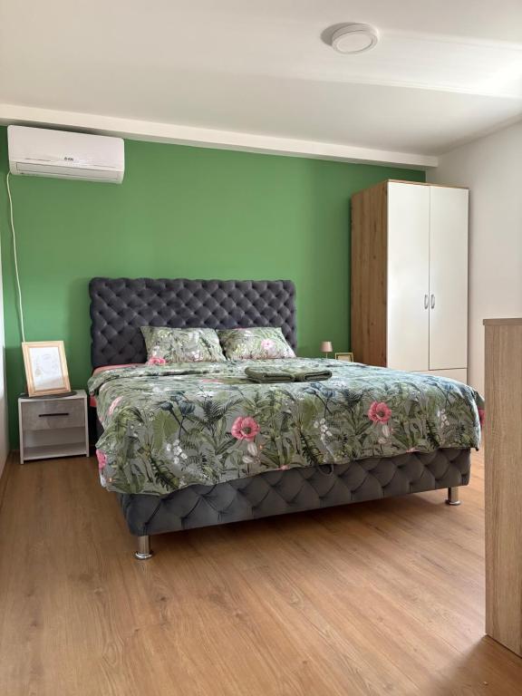 a bedroom with a bed and a green wall at Fenix apartman in Zaječar