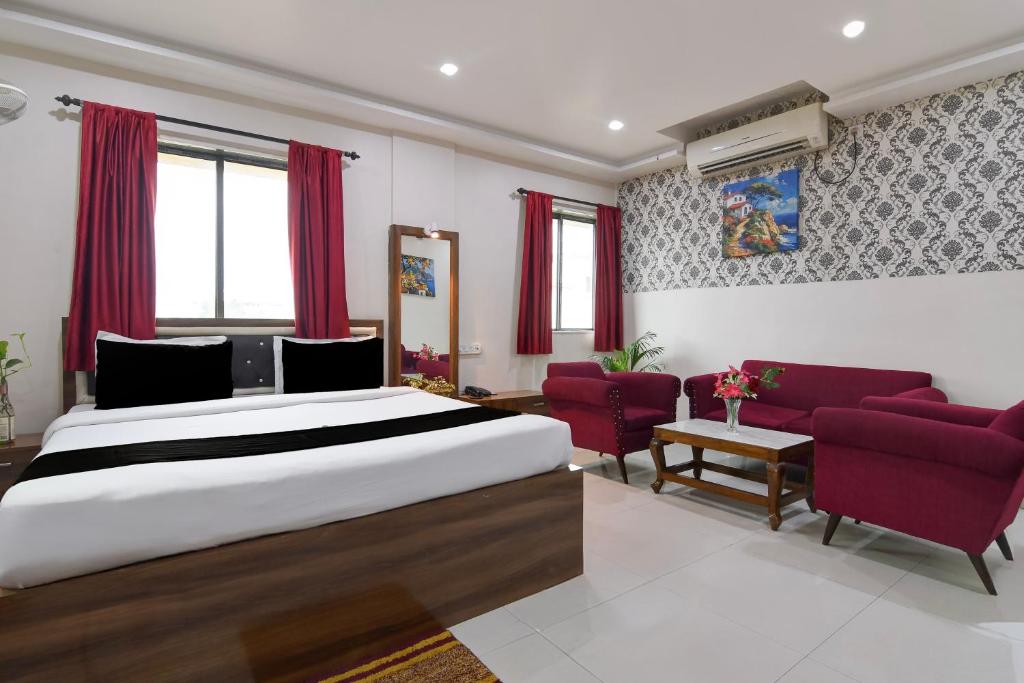 a bedroom with a large bed and red chairs at Townhouse Deshapriya Park Kolkata Formerly DK Inn in Kolkata