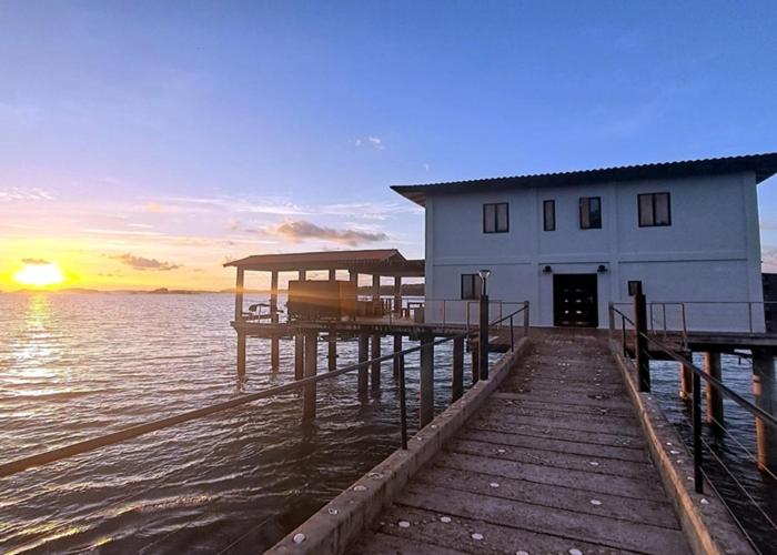 a building on a dock in the water at sunset at Amazing Grace Panamá in Boca Chica