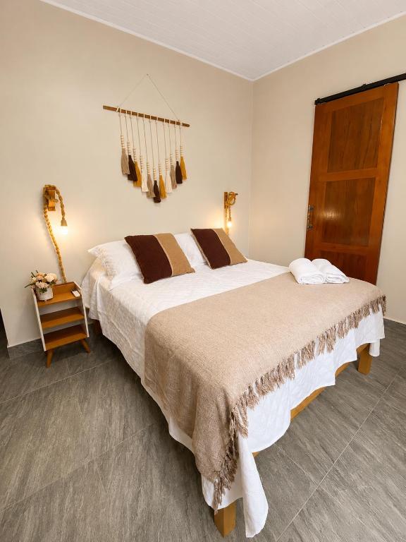 a bedroom with a large bed and a wooden door at Pousada Narval Buzios in Búzios