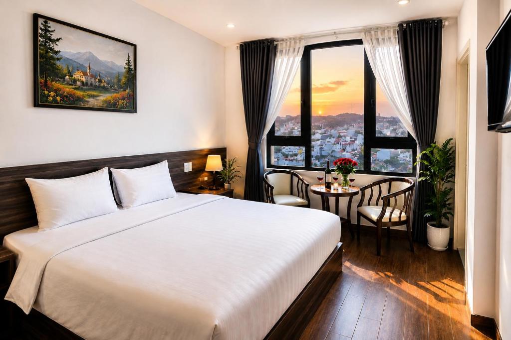 a hotel room with a bed and a table with chairs at Laimeront Dalat Hotel & Apartment in Da Lat