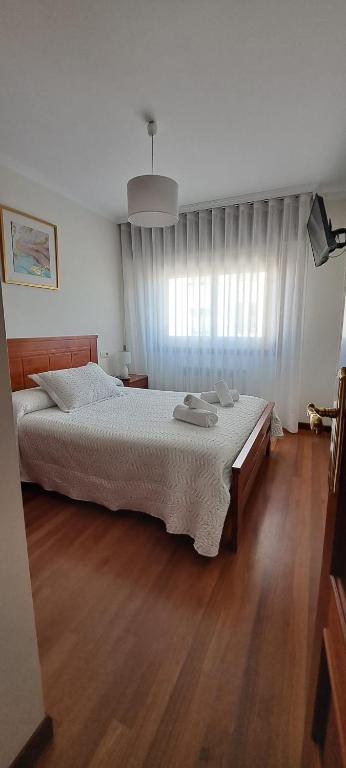 a bedroom with a large bed and a wooden floor at Apartamento Marichu in Melide
