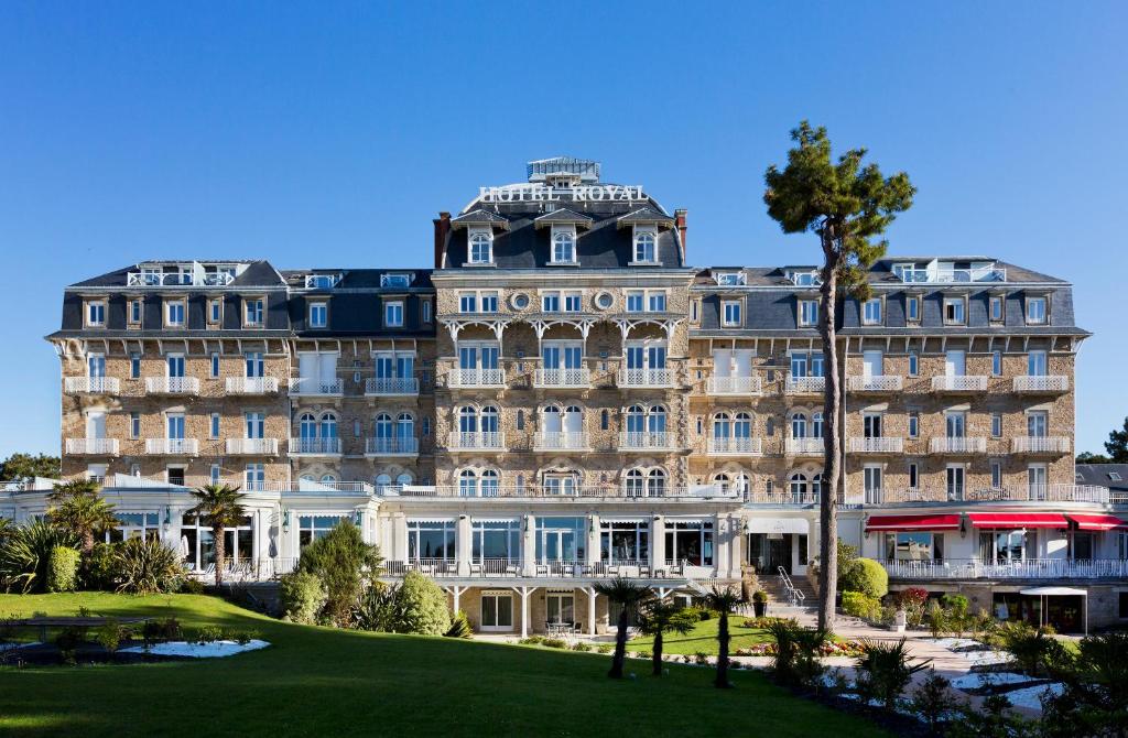 un grand bâtiment avec un palmier en face dans l'établissement Hôtel Barrière Le Royal La Baule, à La Baule