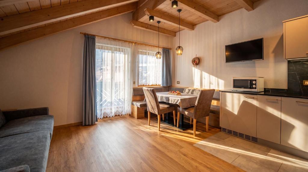 a living room with a kitchen and a table with chairs at Apartments Lasteis in La Villa