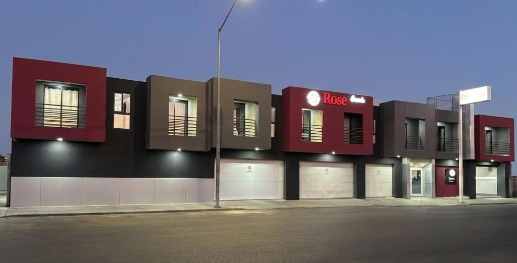 a building with a red and black facade with windows at Hotel Rose Ensenada in Ensenada