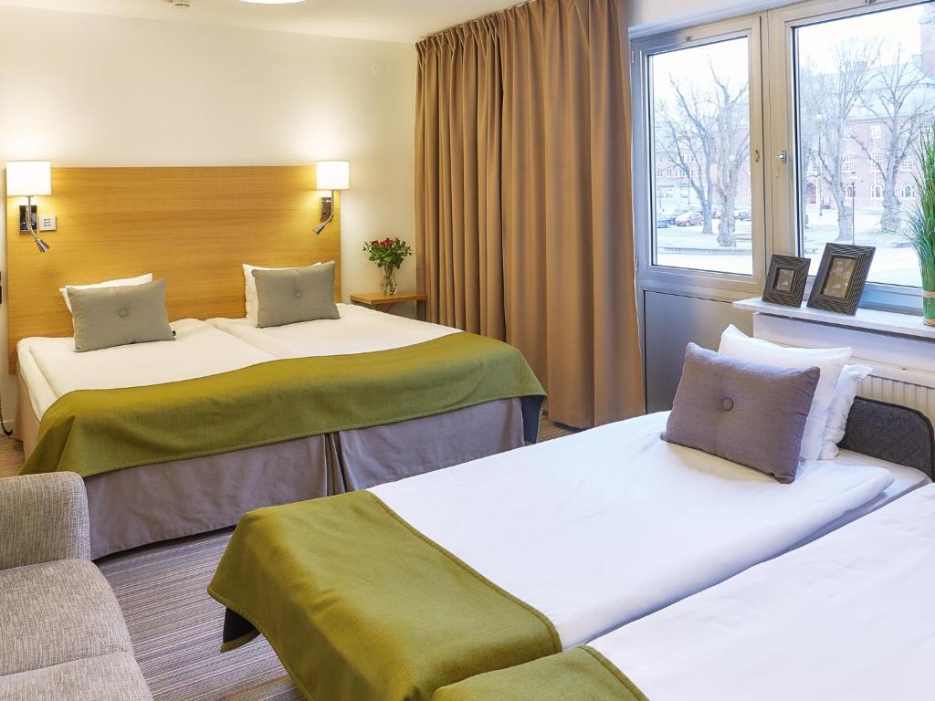 ネッシェーにあるHotell Höglandのベッド2台と窓が備わるホテルルームです。