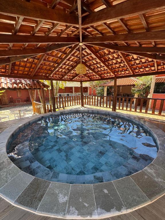 a large swimming pool under a wooden roof at Pousada Encanto dos Anjos in Pirenópolis