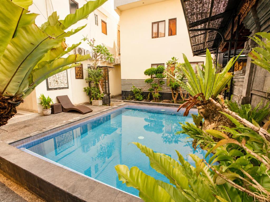 a swimming pool in front of a house with plants at Suardana Inn's in Kuta