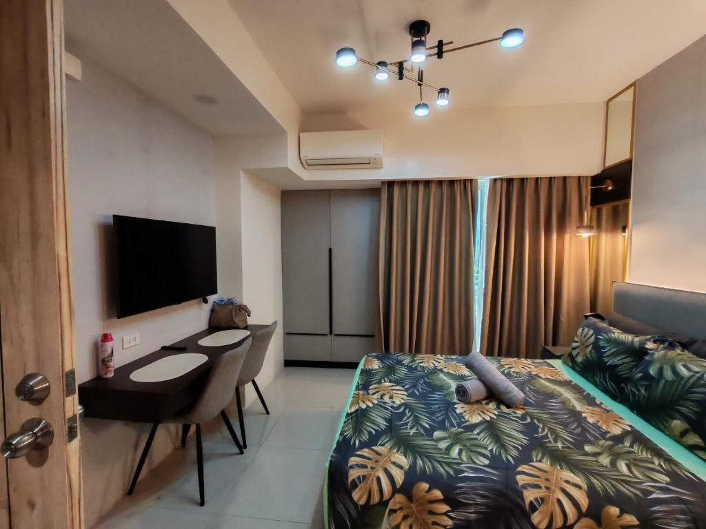 a bedroom with a bed and a desk and a television at inspiria condo davao 14th in Davao City