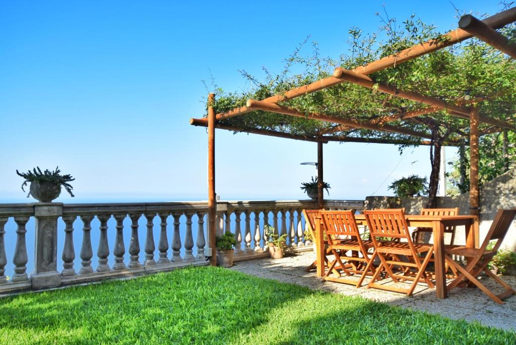 a wooden pergola with chairs and a table on a lawn at Villa Belvedere Amodeo - terrace, seaview, wifi in Conca dei Marini