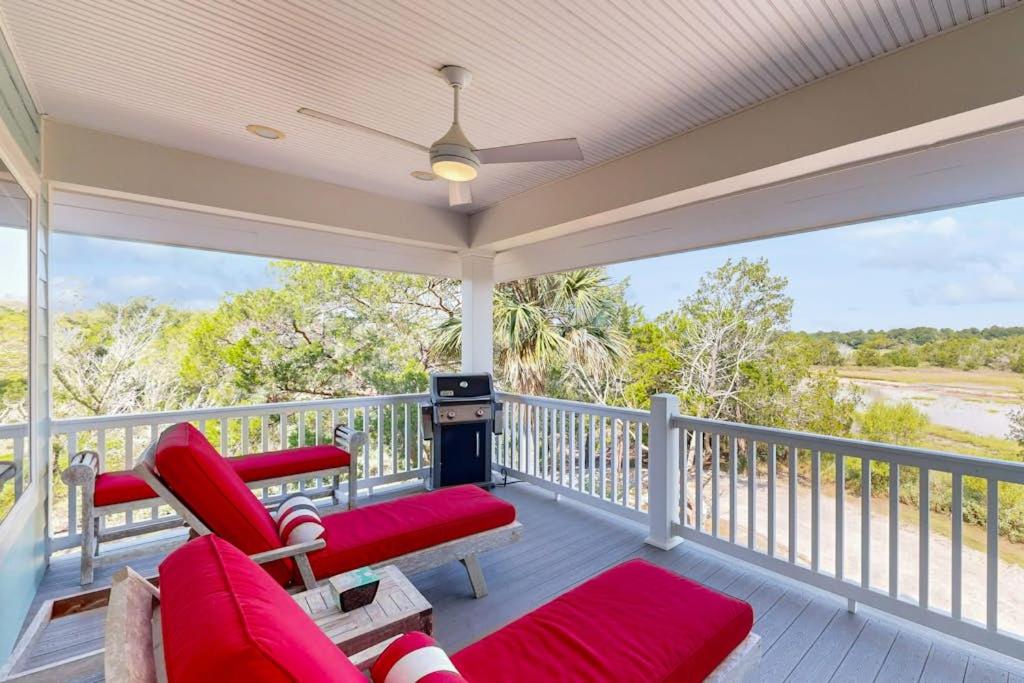 a screened in porch with red chairs and a couch at Sweet Carolina in Edisto Island