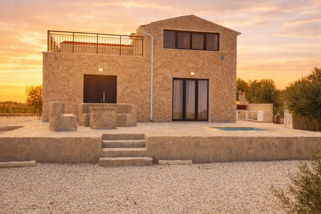 a brick house with a sunset in the background at Olivia Suite in Pano Arodes