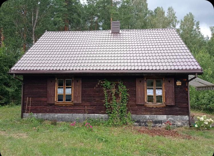 a small wooden house sitting on top of a field at Good Chata Leśna Polana in Dobry Las