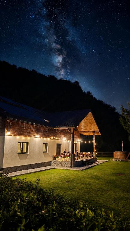a building with a bar in the yard at night at Artizan Chalet in Topliţa
