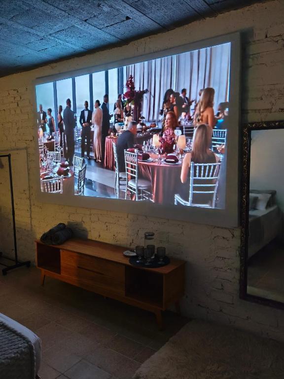 a television screen with a picture of a party on a wall at Suíte Completa com Tela de Cinema in Garanhuns