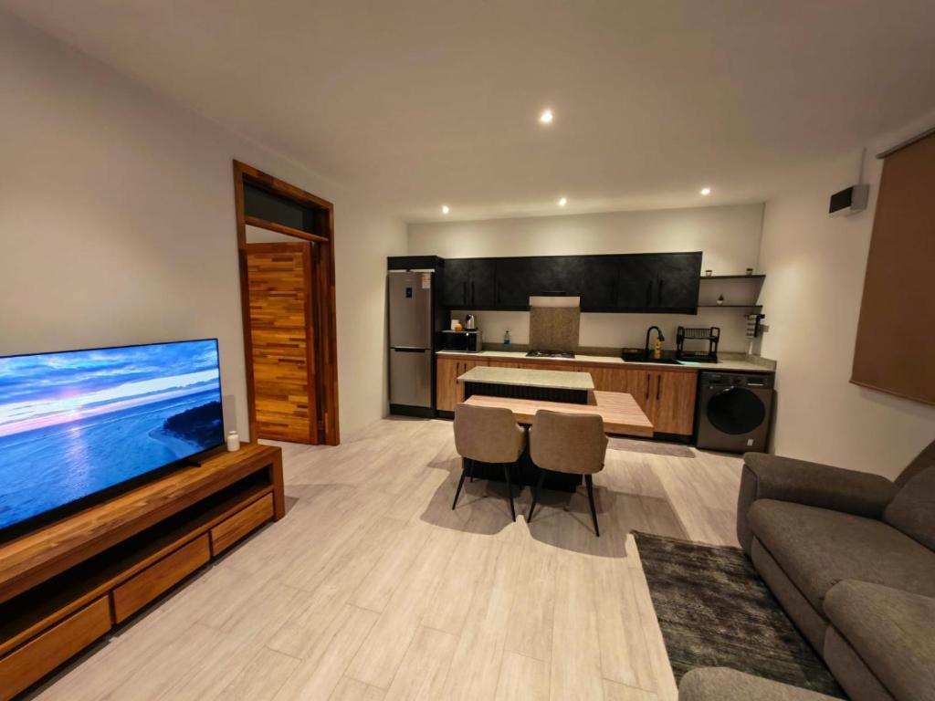 a living room with a large television and a kitchen at RM Westside Apartment in Case Noyale