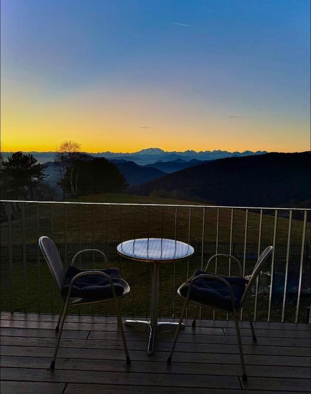 a table and two chairs on a deck with the sunset at Studio on Monte Generoso, peace & nature in Castel San Pietro