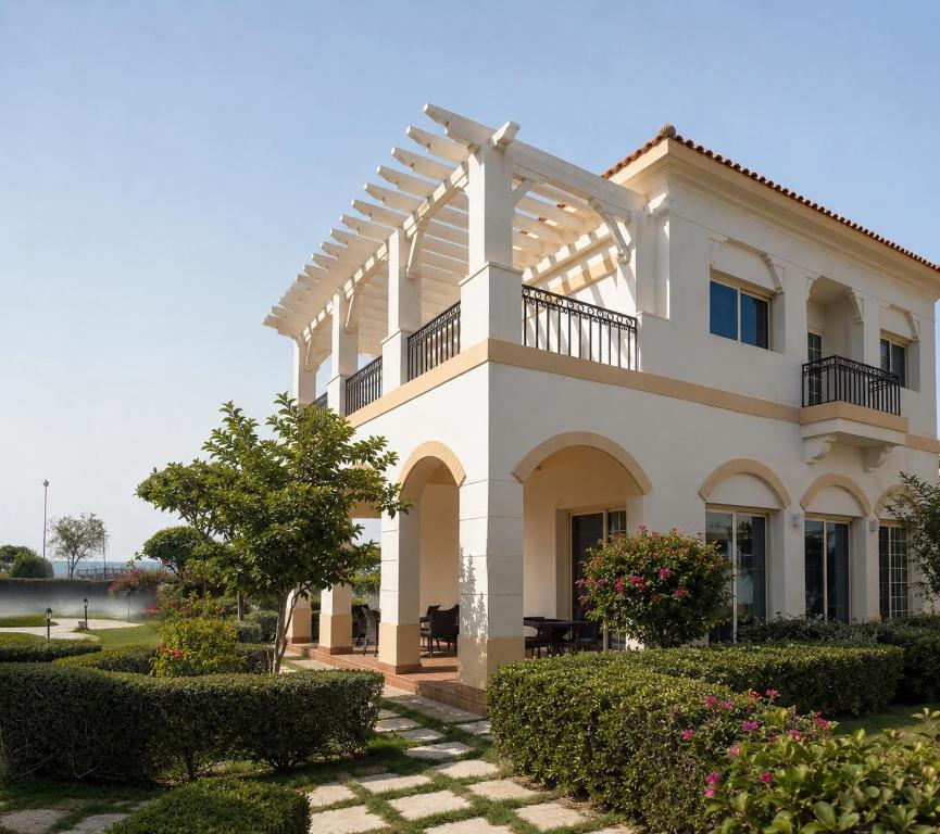 a white house with a balcony and bushes at منتجع موفون بيتش in Al Khobar