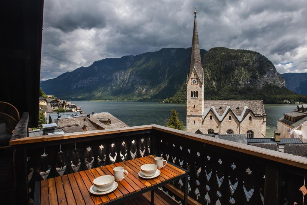 a balcony with a table with cups and a church at Franz 38 - Appartement Hallstatt in Hallstatt