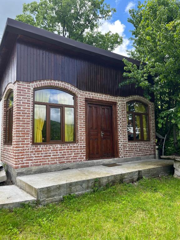 a small brick house with a wooden door at Marisi Cottage - კოტეჯი მარისი in Ambrolauri