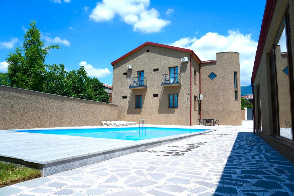 a house with a swimming pool in front of a building at Hotel Kvarlis Mtebi in Kvareli