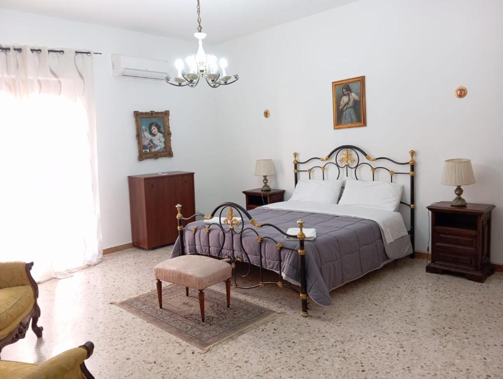 a bedroom with a bed and a chair and a chandelier at Elico Di Sicilia home B in Sambuca di Sicilia