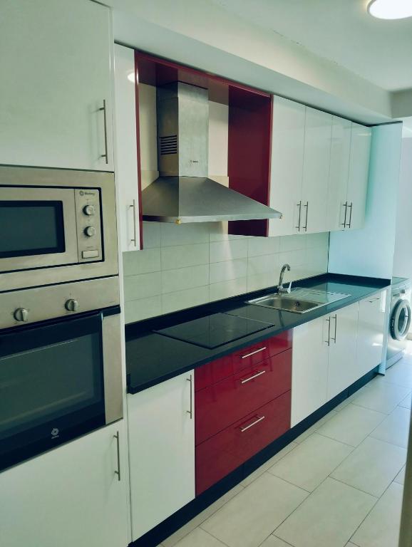 a kitchen with white cabinets and a sink and a microwave at apartamento victor in Cee
