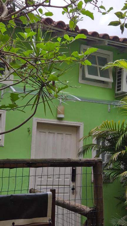 a green house with a white door and a window at Loft Caminho do Mar in Angra dos Reis