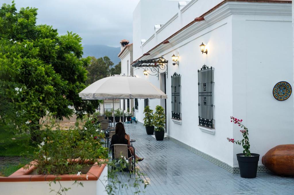 a woman sitting under an umbrella on a patio at Hotel Boutique Alcazaba Salobreña in Salobreña