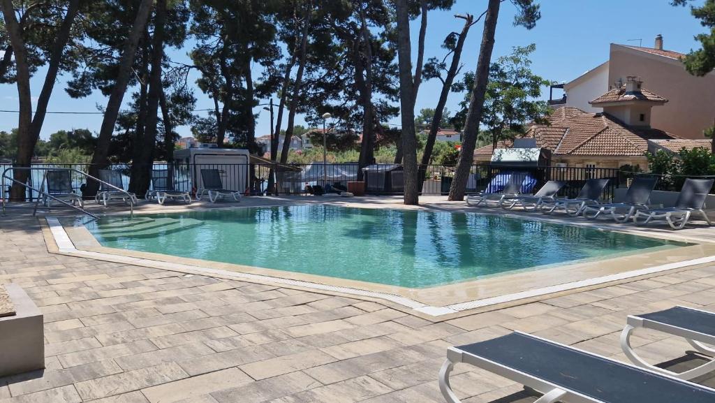 a large swimming pool with chairs and trees at Taber Pašman – Mobile Homes in Pašman
