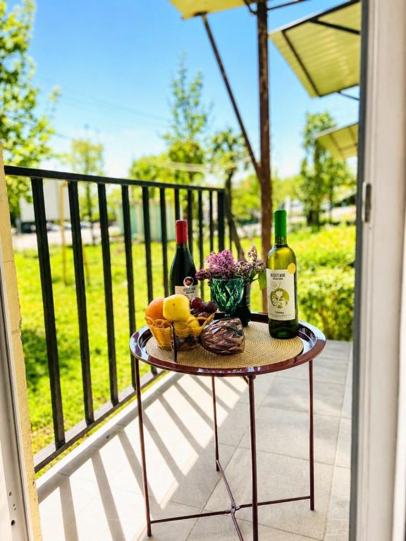 a table with two bottles of wine and fruit on a balcony at Kitesa's apartment with two bedrooms in Mtskheta