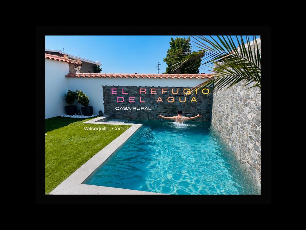 a person swimming in a pool in front of a villa at El Refugio del Agua - Casa Rural in Valsequillo