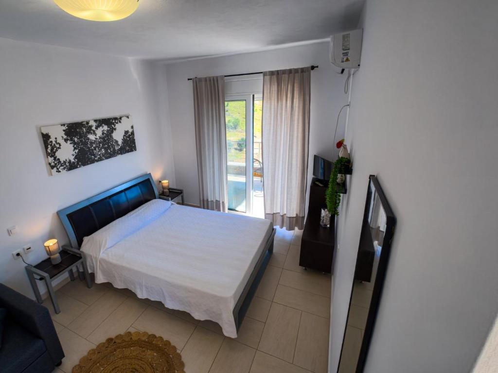 a bedroom with a white bed and a balcony at Billys studios in Karistos