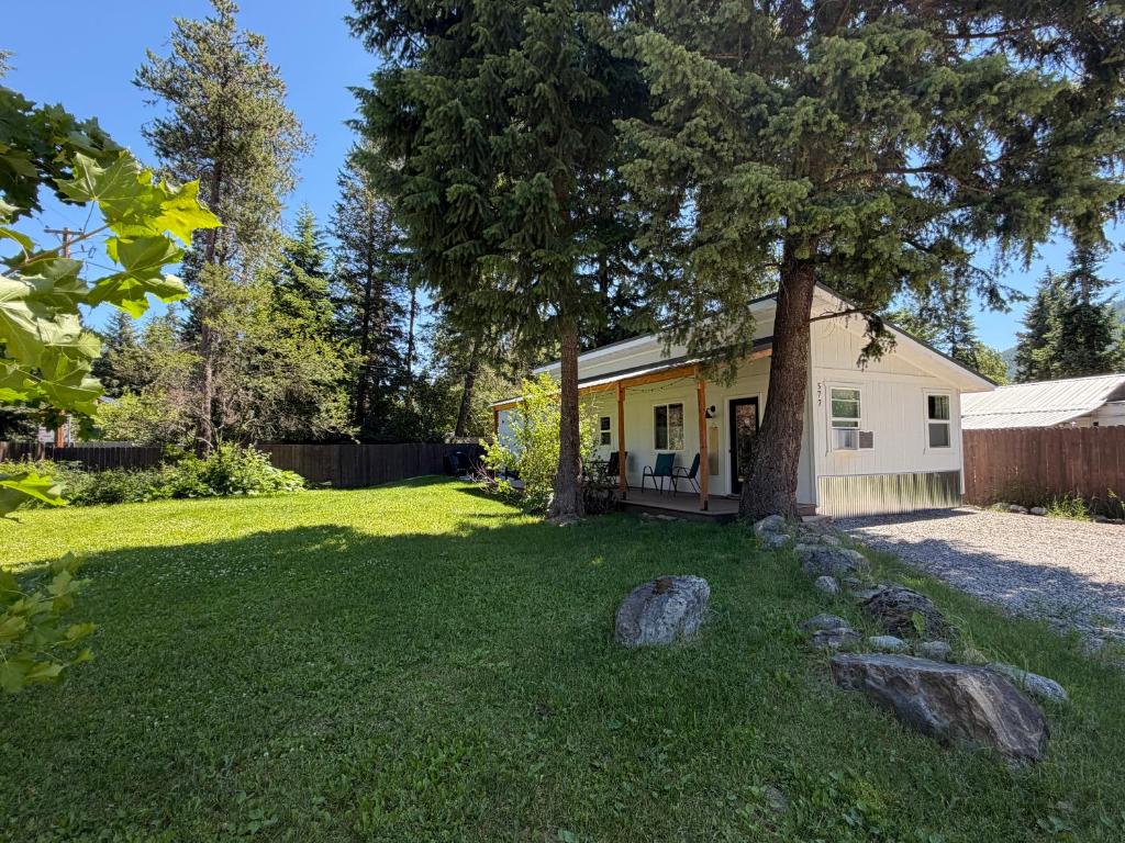 a small yellow house with a tree in the yard at Hidden Gem Cabin in Hungry Horse, Firepit, Close to Glacier in Hungry Horse