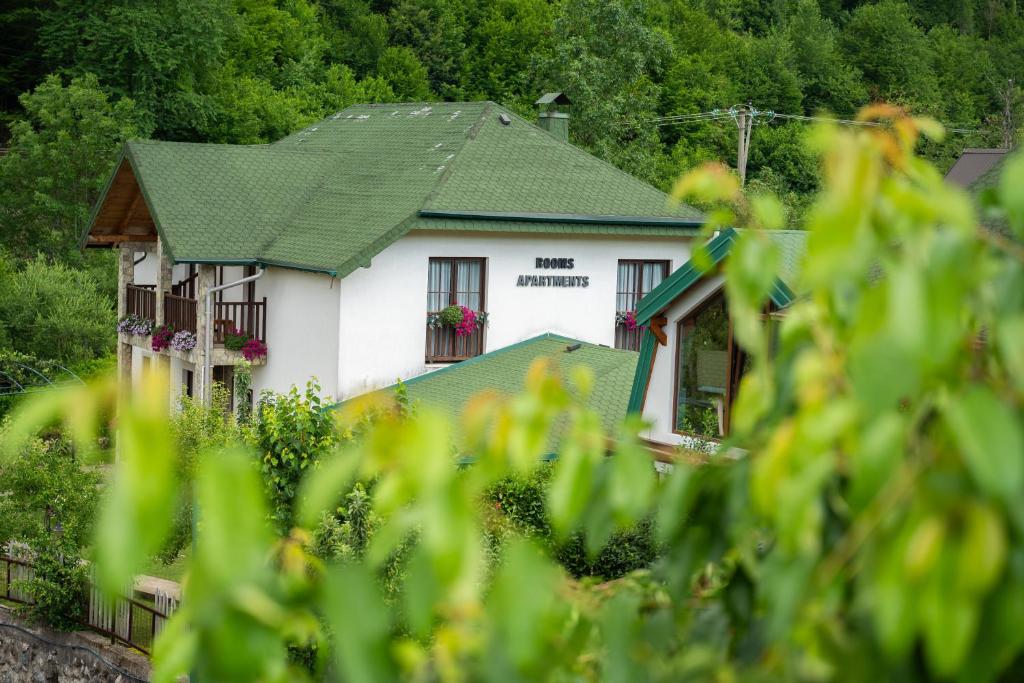 a white house with a green roof at Rooms and apartmants Mirovic in Kolašin
