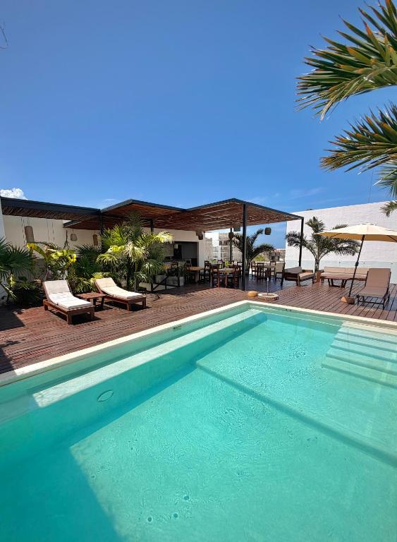a swimming pool with chairs and tables and a patio at Ah Xok suites 5a Avenida in Playa del Carmen